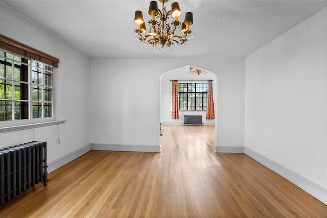 1 Highwood Way, Larchmont, NY 10538 - unfurnished dining area with radiator, a chandelier, wood-type flooring, and arched walkways