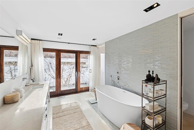 178 Skimhampton Rd, Amagansett, NY 11937 - bathroom with french doors, tile walls, a freestanding tub, vanity, and tile patterned flooring