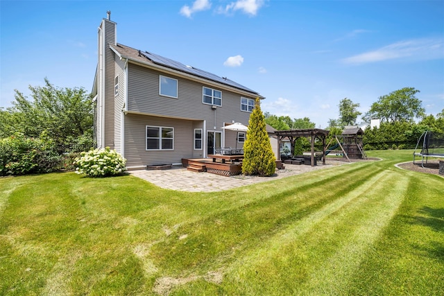 9 June Rd, Chester, NY 10918 - back of house featuring a trampoline, a patio area, a chimney, roof mounted solar panels, and a pergola