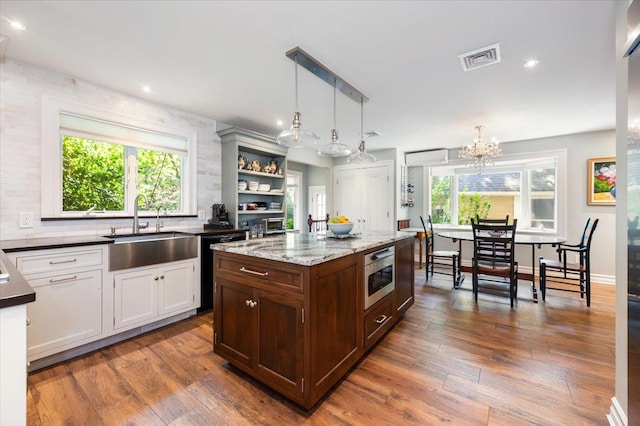 34 Elm St, Great Neck, NY 11021 - kitchen with dishwashing machine, dark wood finished floors, a chandelier, hanging light fixtures, and a center island