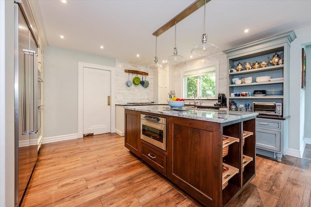 34 Elm St, Great Neck, NY 11021 - kitchen with open shelves, light wood-style floors, light stone countertops, a center island, and recessed lighting