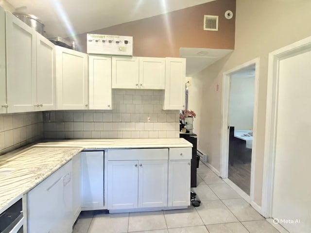 42 Oak Dr, Riverhead, NY 11901 - kitchen with vaulted ceiling, tasteful backsplash, light tile patterned floors, white cabinetry, and light stone counters