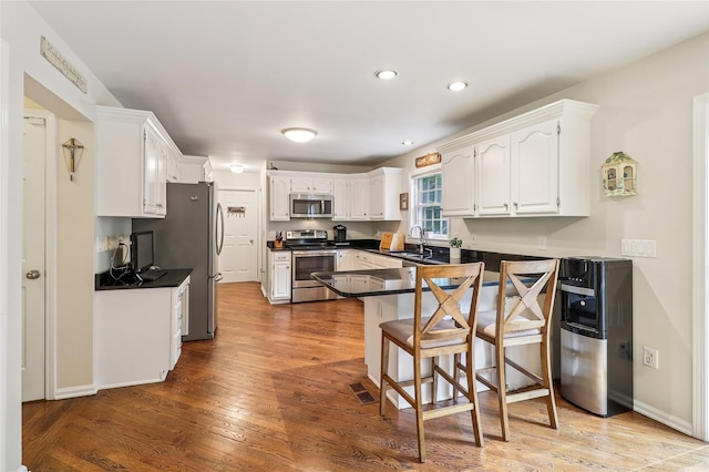 10 Jennifer Ln, Carmel, NY 10512 - kitchen featuring stainless steel appliances, dark countertops, a peninsula, white cabinets, and a breakfast bar