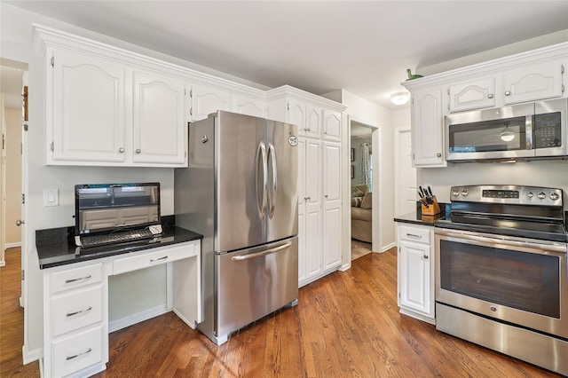 10 Jennifer Ln, Carmel, NY 10512 - kitchen with stainless steel appliances, dark countertops, dark wood finished floors, white cabinets, and a desk