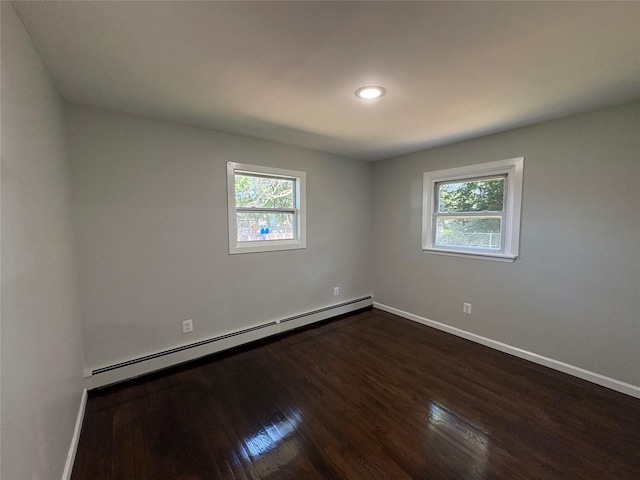 9 Holt St, Amityville, NY 11701 - empty room featuring a baseboard heating unit, healthy amount of natural light, dark wood-style flooring, and recessed lighting