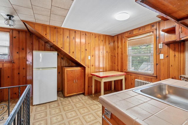 46-27 195th St, Flushing, NY 11358 - kitchen with tile countertops, freestanding refrigerator, wood walls, light floors, and brown cabinets