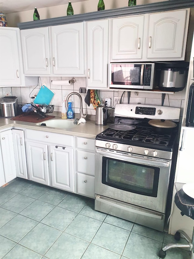 12826 Gotham Rd, South Ozone Park, NY 11420 - kitchen featuring appliances with stainless steel finishes, decorative backsplash, and white cabinetry