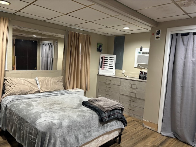 179 Clinton Ave, East Patchogue, NY 11772 - bedroom with wood finished floors, electric panel, a drop ceiling, recessed lighting, and an AC wall unit