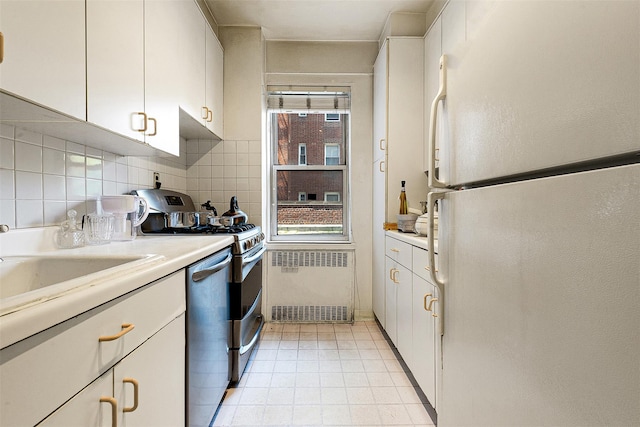 69-10 108th St Unit 1N, Forest Hills, NY 11375 - kitchen featuring stainless steel appliances, radiator, light countertops, white cabinetry, and decorative backsplash