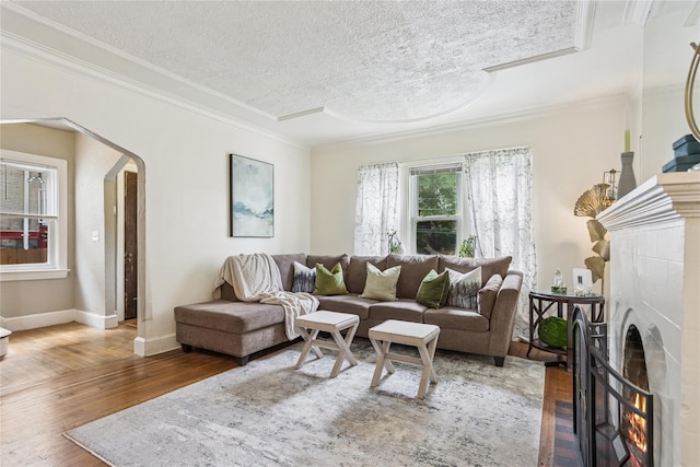 222 E 4th St, Mount Vernon, NY 10553 - living room featuring crown molding, a textured ceiling, wood finished floors, arched walkways, and a warm lit fireplace