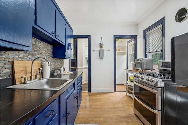 222 E 4th St, Mount Vernon, NY 10553 - kitchen with blue cabinets, double oven range, tasteful backsplash, light wood-type flooring, and freestanding refrigerator