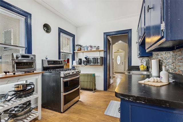 222 E 4th St, Mount Vernon, NY 10553 - kitchen featuring appliances with stainless steel finishes, radiator heating unit, blue cabinetry, and plenty of natural light