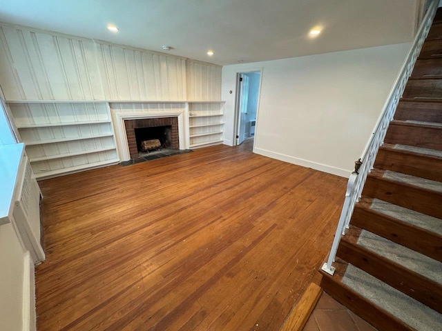 390 Atlantic Ave, East Rockaway, NY 11518 - unfurnished living room featuring stairs, wood finished floors, a brick fireplace, and recessed lighting
