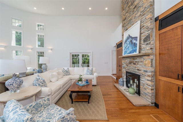 4510 Peconic Bay Blvd, Laurel, NY 11948 - living room featuring light wood-style flooring, healthy amount of natural light, a towering ceiling, a stone fireplace, and recessed lighting