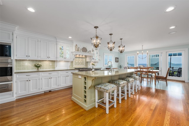 4510 Peconic Bay Blvd, Laurel, NY 11948 - kitchen featuring stainless steel oven, a chandelier, built in microwave, white cabinetry, and a breakfast bar area