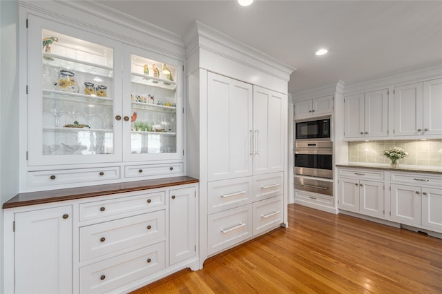 4510 Peconic Bay Blvd, Laurel, NY 11948 - bar area featuring oven, black microwave, decorative backsplash, light wood finished floors, and crown molding