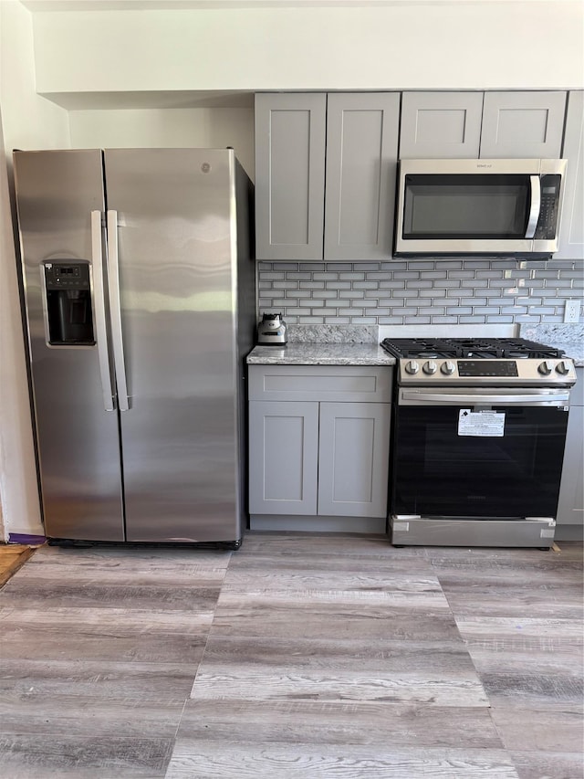 1319 Hicks St, Bronx, NY 10469 - kitchen featuring appliances with stainless steel finishes, gray cabinetry, and tasteful backsplash