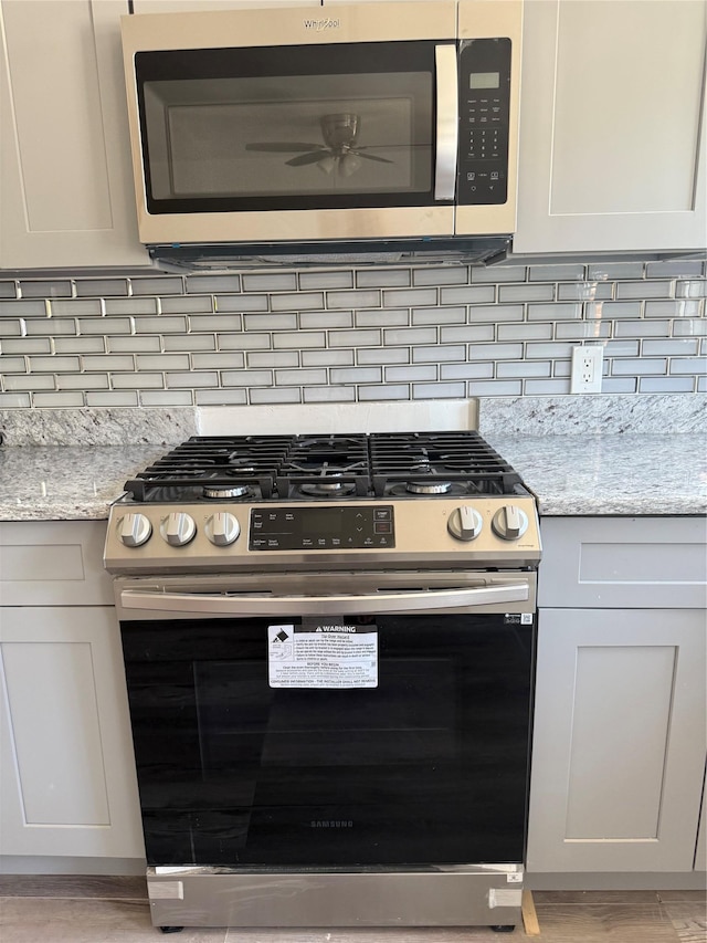 1319 Hicks St, Bronx, NY 10469 - kitchen view of appliances with stainless steel finishes, a ceiling fan, tasteful backsplash, and light stone counters