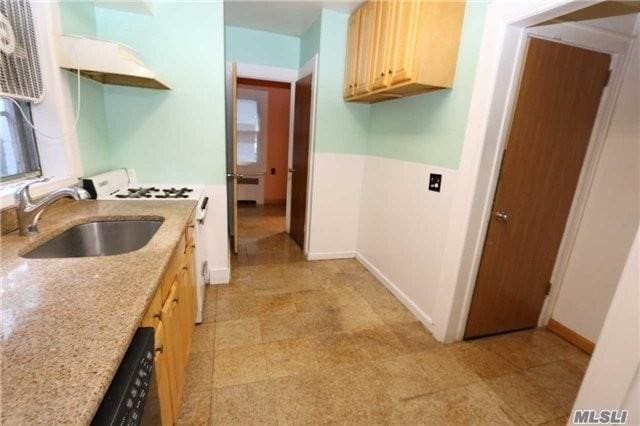 85-24 Eton St, Jamaica Estates, NY 11432 - kitchen featuring white range with gas stovetop, light brown cabinets, light stone countertops, light floors, and premium range hood