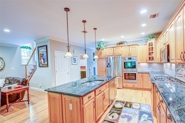 122 Cambon Ave, Saint James, NY 11780 - kitchen featuring appliances with stainless steel finishes, ornamental molding, light wood finished floors, glass insert cabinets, and an island with sink