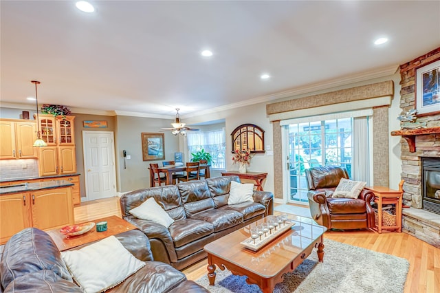 122 Cambon Ave, Saint James, NY 11780 - living room with a stone fireplace, crown molding, recessed lighting, light wood-type flooring, and ceiling fan