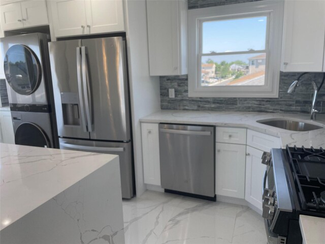 503 Nassau Ave, Freeport, NY 11520 - kitchen featuring stainless steel appliances, stacked washing machine and dryer, light marble finish flooring, and tasteful backsplash