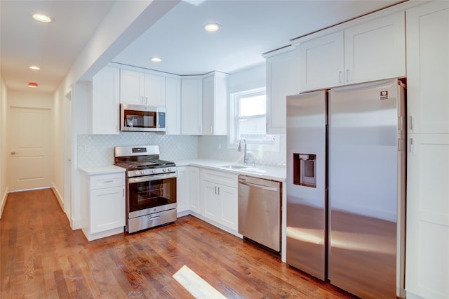 89-25 127th St, Richmond Hill, NY 11418 - kitchen with appliances with stainless steel finishes, decorative backsplash, light countertops, white cabinets, and light wood-style floors