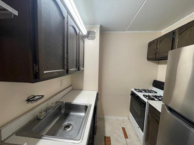 100 Clinton Ave Unit 3P, Mineola, NY 11501 - kitchen with freestanding refrigerator, white range with gas stovetop, light countertops, dark brown cabinetry, and ornamental molding