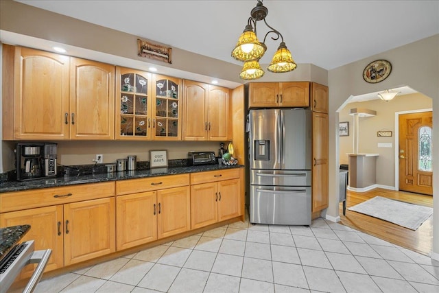 17 Acorn Rd, East Rockaway, NY 11518 - kitchen with stainless steel fridge, arched walkways, glass insert cabinets, light tile patterned floors, and dark stone counters