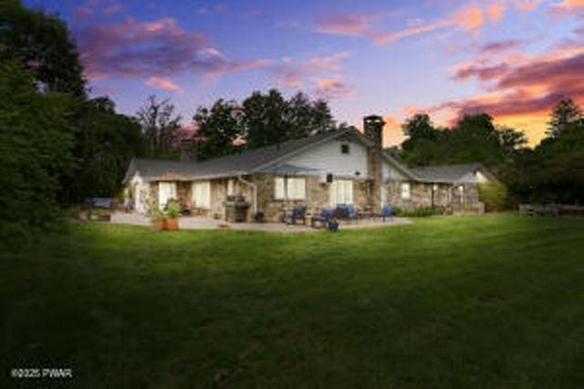 312 E Ann St, Milford, PA 18337 - back of property at dusk featuring a chimney, a patio, and a lawn