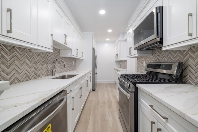 85 S Centre Ave Unit A17, Rockville Centre, NY 11570 - kitchen with stainless steel appliances, white cabinets, recessed lighting, decorative backsplash, and light wood-style flooring