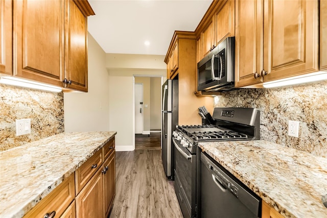 609 NE Palmer Rd Unit 4J, Yonkers, NY 10701 - kitchen featuring appliances with stainless steel finishes, light stone countertops, light wood-style flooring, and brown cabinets
