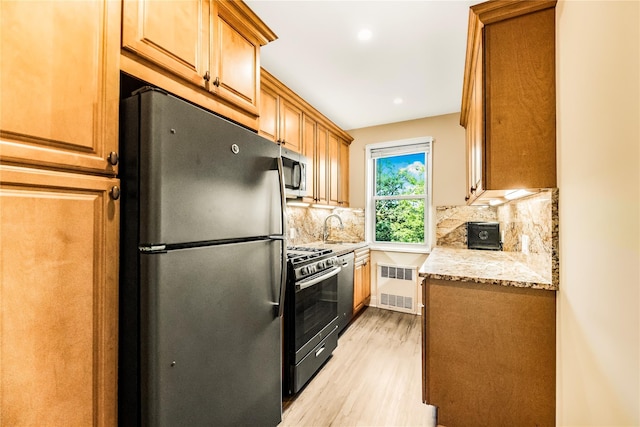 609 NE Palmer Rd Unit 4J, Yonkers, NY 10701 - kitchen featuring stainless steel appliances, radiator, light wood-style floors, backsplash, and light stone countertops