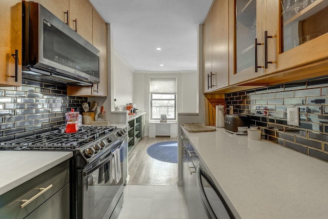 5 Birchwood Ct Unit 4N, Mineola, NY 11501 - kitchen featuring stainless steel microwave, range with gas stovetop, light countertops, crown molding, and backsplash