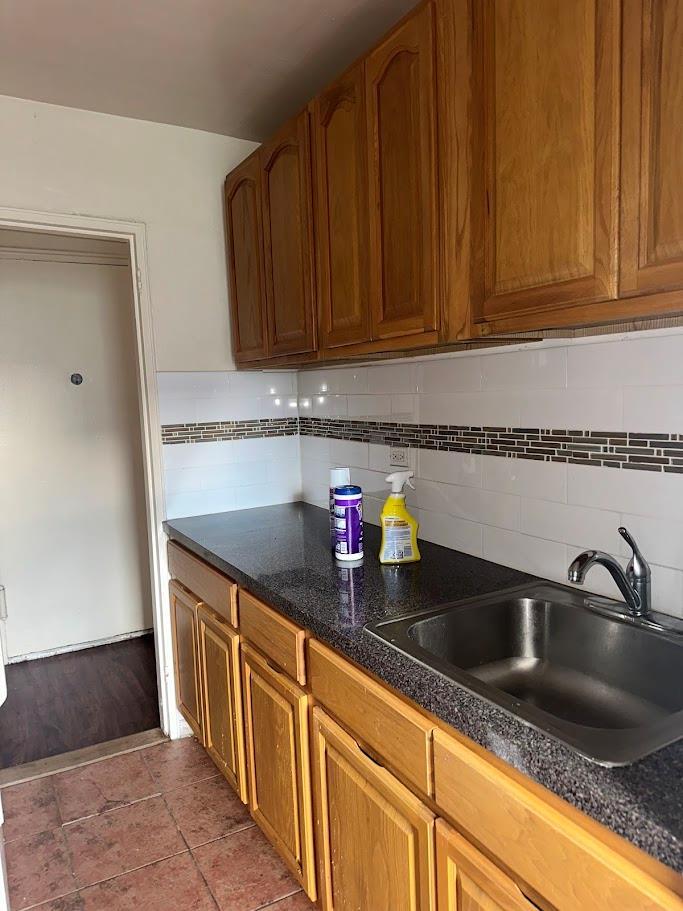 2385 Barker Ave Unit 6B, Bronx, NY 10467 - kitchen featuring backsplash, dark countertops, and brown cabinets