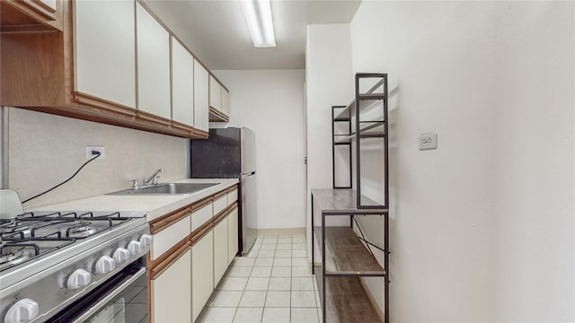 8420 153rd Ave Unit 6H, Howard Beach, NY 11414 - kitchen with gas range oven, freestanding refrigerator, light countertops, light tile patterned floors, and white cabinets