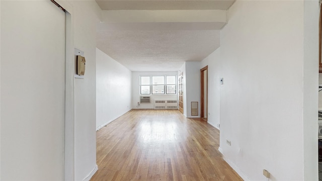 8420 153rd Ave Unit 6H, Howard Beach, NY 11414 - corridor with radiator heating unit, light wood-style floors, a wall mounted air conditioner, and a textured ceiling