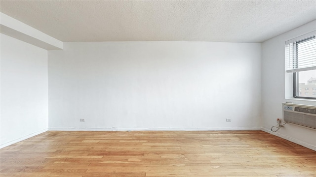 8420 153rd Ave Unit 6H, Howard Beach, NY 11414 - unfurnished room with light wood-style floors, a textured ceiling, and an AC wall unit