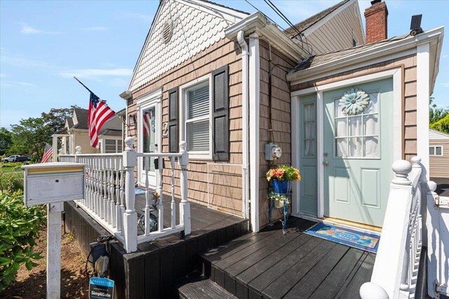2 Croydon Dr, North Bellmore, NY 11710 - view of exterior entry featuring a chimney and a wooden deck