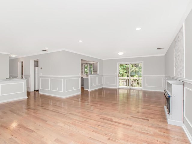 237 Brady Ave, Hawthorne, NY 10532 - unfurnished living room featuring a decorative wall, a fireplace, light wood-style floors, ornamental molding, and wainscoting
