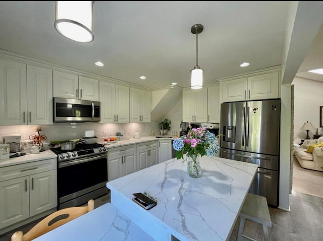 48 Marlene Dr, Syosset, NY 11791 - kitchen with stainless steel appliances, white cabinetry, decorative light fixtures, light stone counters, and wood finished floors