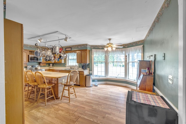 2 Gerri Ct, Wallkill, NY 12589 - kitchen featuring appliances with stainless steel finishes, light countertops, light wood-style floors, a kitchen breakfast bar, and brown cabinets
