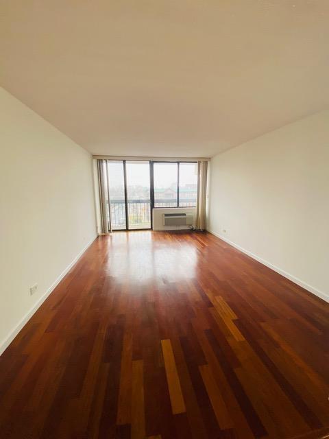 15038 Union Tpke Unit 3D, Kew Garden Hills, NY 11367 - spare room featuring dark wood-type flooring, a wall mounted air conditioner, and expansive windows