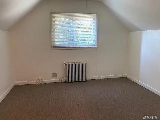 116-46 171st St, Jamaica, NY 11434 - bonus room with radiator heating unit, vaulted ceiling, and dark colored carpet