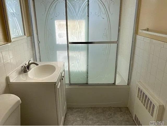 116-46 171st St, Jamaica, NY 11434 - full bathroom with tile walls, vanity, and bath / shower combo with glass door
