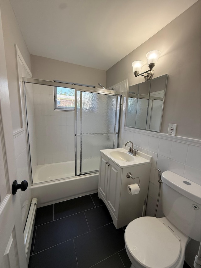 77 Adams Rd Unit 1D, Central Islip, NY 11722 - full bathroom with a baseboard radiator, vanity, bath / shower combo with glass door, tile patterned flooring, and tile walls