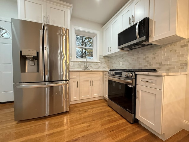 4223 Boyd Ave, Bronx, NY 10466 - kitchen with appliances with stainless steel finishes, light countertops, light wood-type flooring, white cabinets, and backsplash