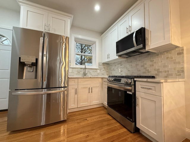 4223 Boyd Ave, Bronx, NY 10466 - kitchen featuring appliances with stainless steel finishes, light wood finished floors, light countertops, white cabinets, and backsplash