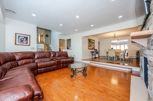 3478 Woodward St, Oceanside, NY 11572 - living area featuring wood finished floors, stairs, a stone fireplace, crown molding, and recessed lighting