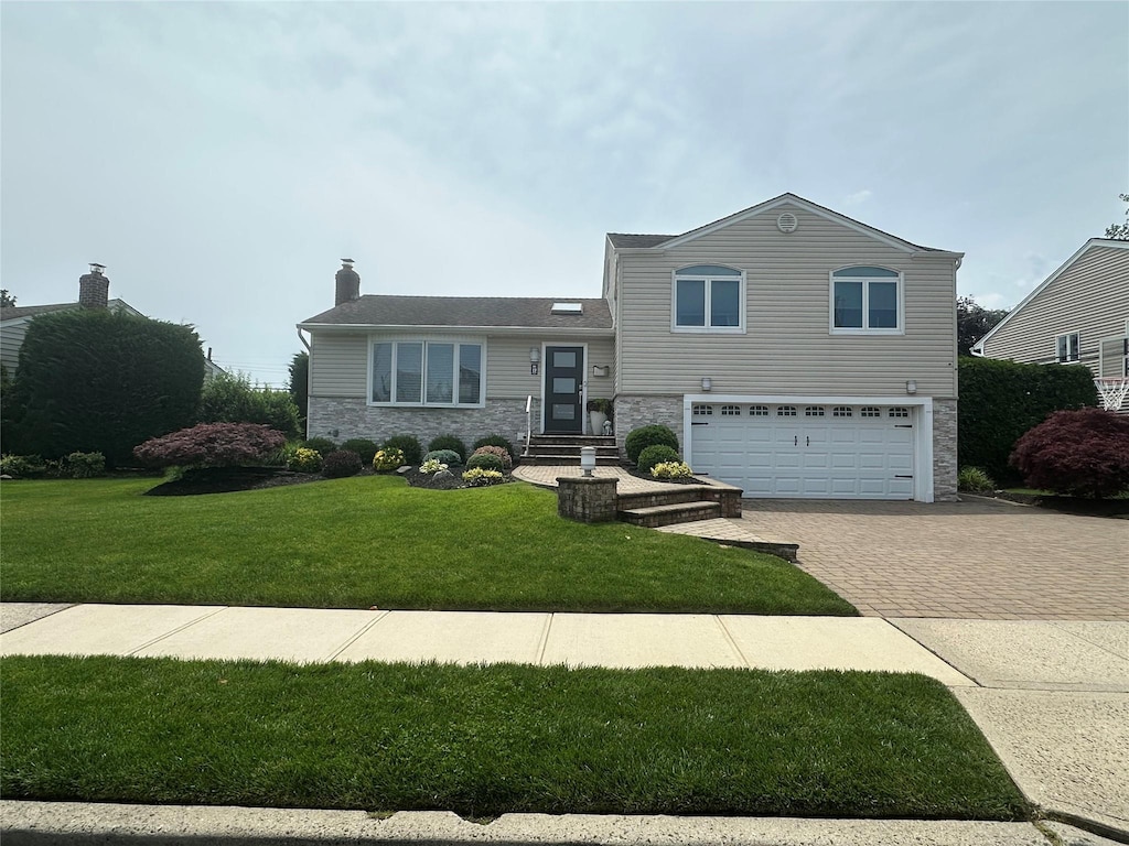17 Keswick Ln, Plainview, NY 11803 - tri-level home with stone siding, decorative driveway, an attached garage, a front lawn, and a chimney